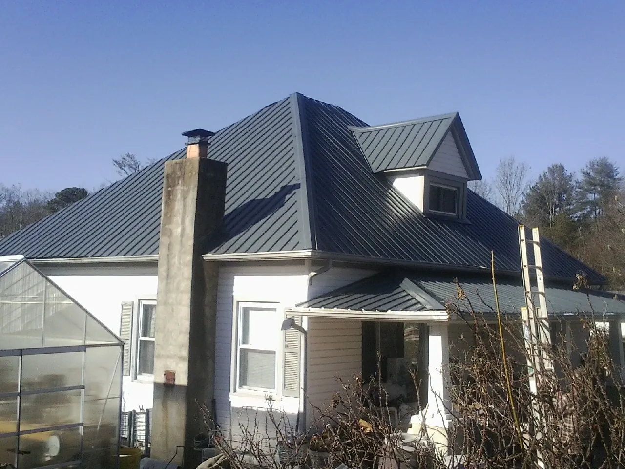 Dark blue standing seam metal roof on a white farmhouse with dormer — Slate & Tile Roof Repair by Roofing Brothers in Atlantic