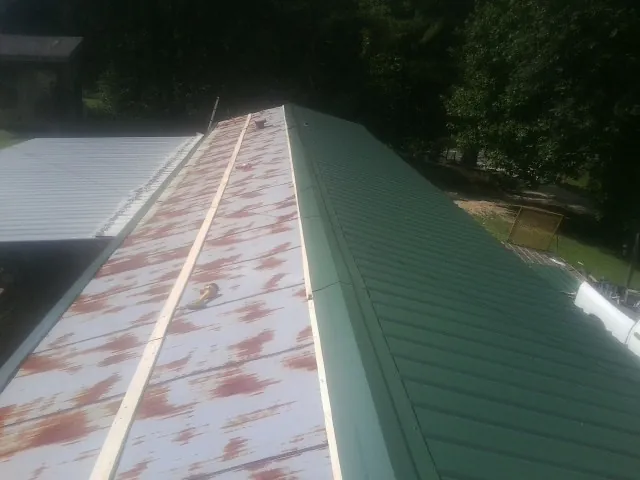 Old rusted panels beside newly installed green metal roofing — Wind Damage Roof Repair by Roofing Brothers in Atlantic