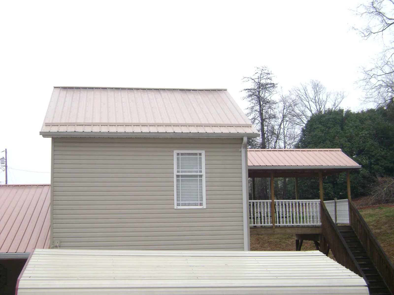 Tan metal roofs on a two story addition and attached porch, from a Roof Replacement job in Atlantic